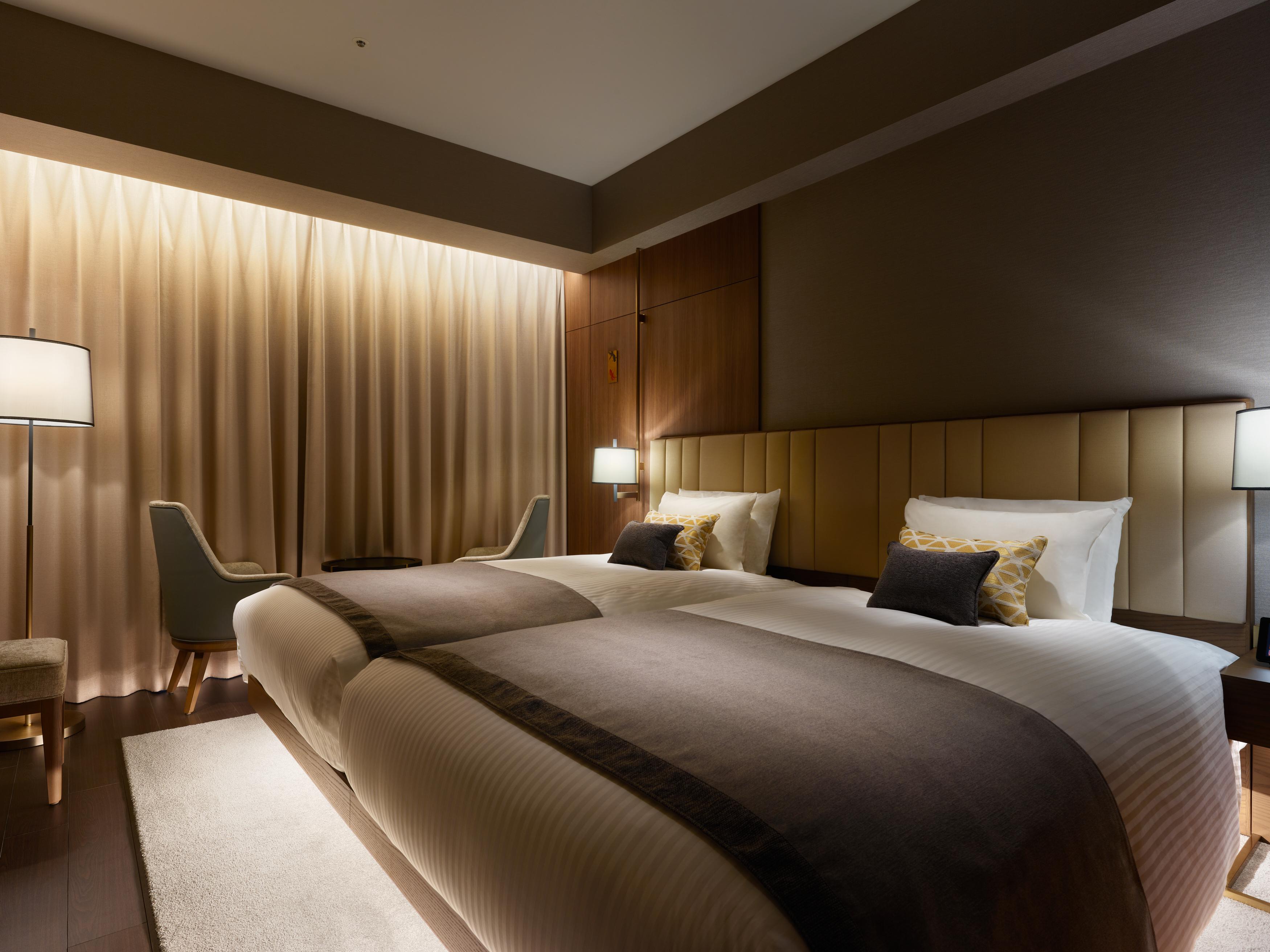 Mitsui Garden Hotel Roppongi Tokyo Premier Esterno foto The photo shows a modern hotel room featuring two twin beds with elegant bedding. The room is adorned with soft, neutral tones and has a warm ambiance created by subtle lighting. A pair of bedside lamps provide additional light, and there is a cozy c