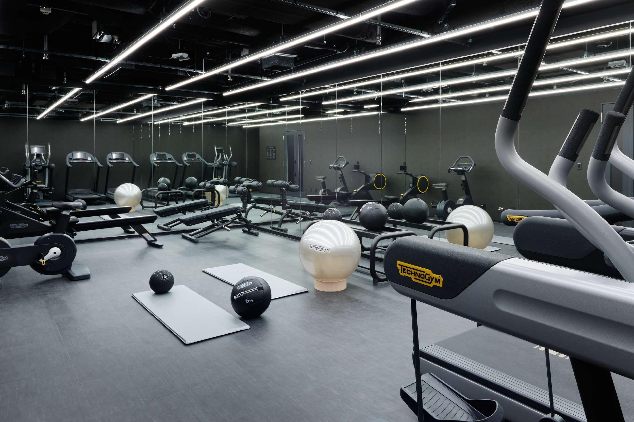Mitsui Garden Hotel Roppongi Tokyo Premier Esterno foto The photo shows a modern gym interior. The space features various exercise equipment, including cardio machines like treadmills and elliptical trainers, weight machines, and free weights. There are also exercise mats and fitness balls scattered throu